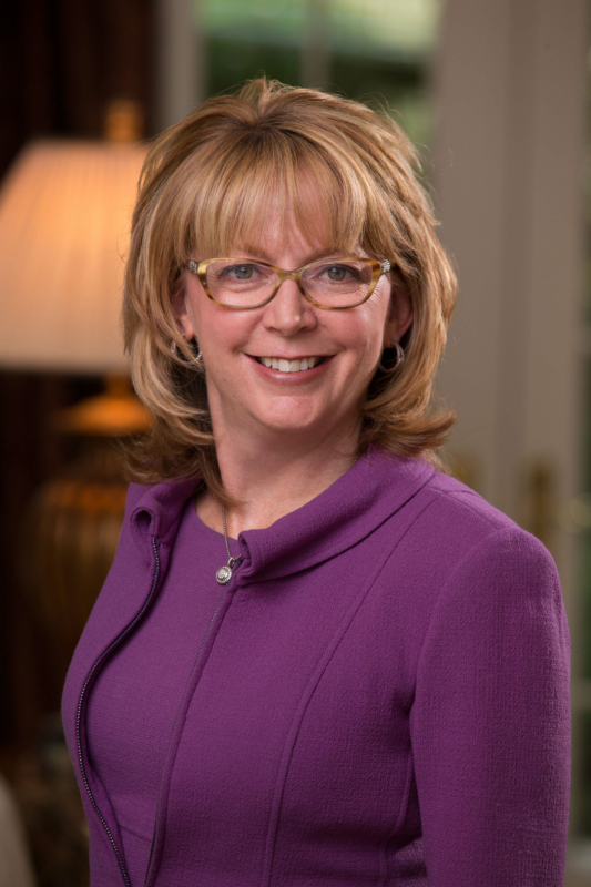 Deborah Majoras, P&G's Chief Legal Officer, wears a plum blouse and looks to camera.