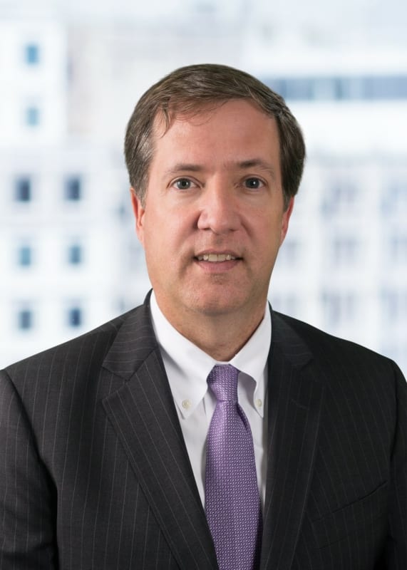 Brian Whisler, Baker McKenzie, looks to camera. A man in a suit with a purple tie.